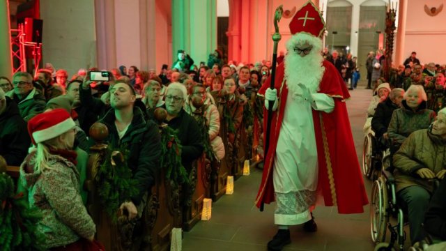 Das Foto zeigt, wie eine als Nikolaus verkleidete Person durch den Mittelgang der Basilika geht.