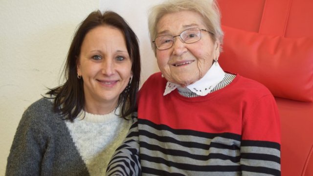 Zwei Frauen hocken/sitzen nebeneinander.